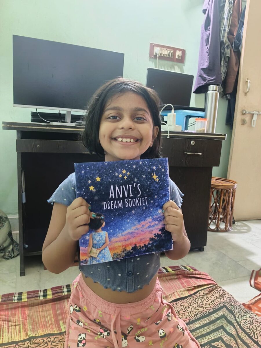 Anvi holding her own DreamBooklet, beaming
